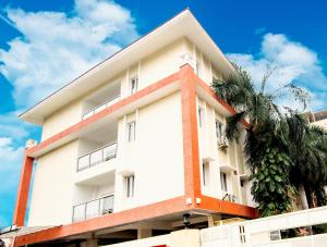 海得拉巴Skyla Serviced Apartments的一座白色的建筑,前面有棕榈树