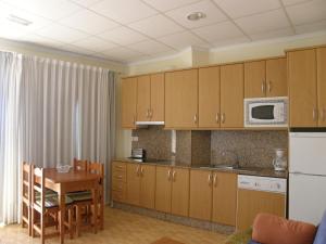 马萨龙港Apartamentos Bellavista的厨房配有木制橱柜、桌子和微波炉