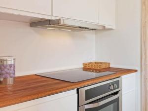 古兹耶姆4 person holiday home in Gudhjem的厨房配有白色橱柜和炉灶烤箱。