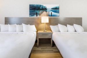 魁北克市Repotel Aéroport Québec的酒店客房设有两张床和一张带台灯的桌子。