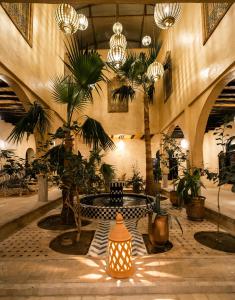 梅尔祖卡莫哈乌特古堡酒店的大堂设有桌子、棕榈树和吊灯