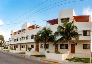 女人岛Villas Najo' Isla Mujeres.的一座白色的建筑,前面有棕榈树