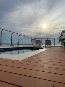 恩卡纳西翁Monoambiente a 400 metros de la playa的大楼内带椅子的甲板和游泳池