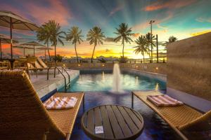 若昂佩索阿哈德曼普拉亚酒店的一个带椅子的游泳池和一个享有日落美景的喷泉
