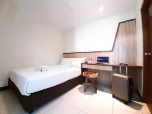 三宝垄Hotel Pantes Kota Lama Semarang的酒店客房,带一张床和行李箱