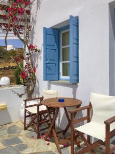 Áno MeriáAnatoli的一张桌子和椅子,位于带蓝色百叶窗的窗户前