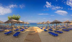 内亚卡瓦里Aelia Seaside Luxury Suites的沙滩上的一把椅子和遮阳伞