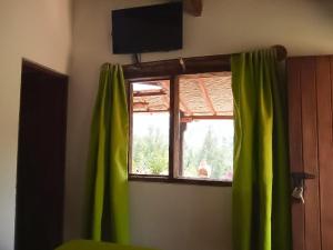 拉基拉Posada El Artesano De Raquira的配有绿窗帘的窗户和电视