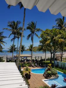 圣塞巴斯蒂安Brisa do Mar Barê Praia Hotel - Praia de BAREQUEÇABA的享有带游泳池和棕榈树的度假村的景致