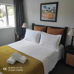 奥克兰Castor Bay Homestay的卧室配有一张带白色床单和枕头的大床。