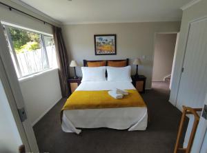 奥克兰Castor Bay Homestay的一间卧室配有一张带黄色毯子的大床