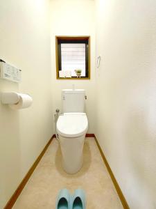 挂川市White Space的一间带卫生间的浴室,配有窗户和蓝色拖鞋