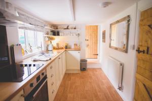 Ormesby Saint MichaelHectors house的厨房铺有木地板,配有白色橱柜。