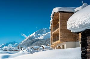 利维尼奥Vetta Alpine Relax的一座被雪覆盖的建筑,背景是一座山