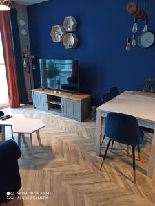 罗兹Nowoczesny Apartament przy Manufakturze z parkingiem podziemnym i klimatyzacją的客厅拥有蓝色的墙壁和桌椅