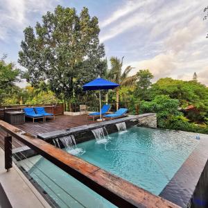 圣卢西亚圣卢西亚山顶住宿加早餐旅馆的一个带瀑布、蓝色椅子和遮阳伞的游泳池