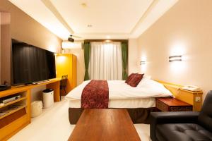 松山松山自由酒店（仅限成人） 的配有一张床和一台平面电视的酒店客房