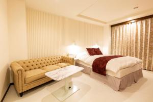 松山松山自由酒店（仅限成人） 的酒店客房,配有床和沙发