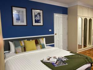 曼谷UHG阿索克素坤逸酒店的一间卧室设有一张蓝色墙壁的大床