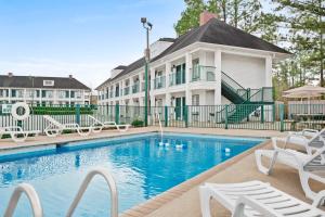 阿梅里克斯戴斯阿美酒店的一座带白色椅子的房子前的游泳池