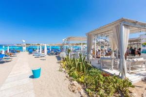 托雷桑塔萨宾娜Villa Irene的海滩上设有桌椅,大海上设有沙滩