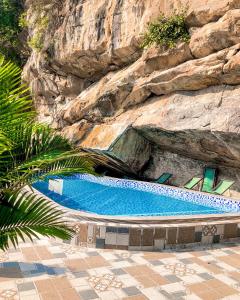 宁平Trang An Memory Homestay的岩石墙旁边的大型游泳池