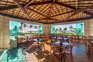 塞古罗港奎塔多索海滩酒店的一间设有桌椅的餐厅,种植了棕榈树
