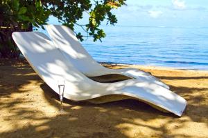 Tohautu米提拉帕别墅酒店的坐在水边的沙子上的白色椅子