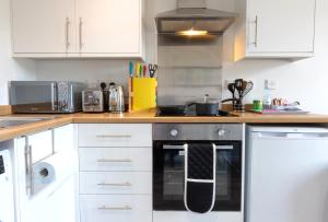 普雷斯顿City Haven Preston Apartments的厨房配有白色橱柜和黑烤箱。