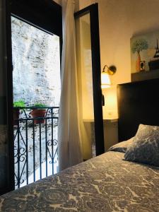 塞特尼尔Casa Bajo la Roca的一间卧室设有一张床,并有通往阳台的门