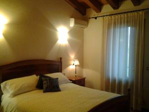 脉泽菲奥雷梅洛度假农庄酒店的一间卧室配有一张床、两盏灯和一个窗户。