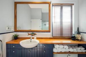 惠灵顿Waterfront 2-bed cottage, Karaka Bays的浴室配有盥洗盆、镜子和毛巾