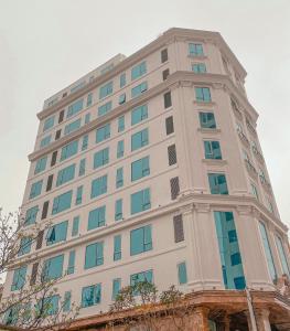 格卢市社Kingdom Hotel Cua Lo的一座高大的白色建筑,设有蓝色的窗户