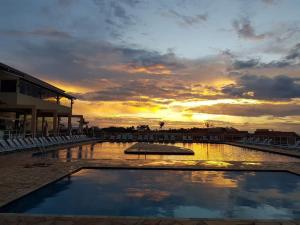 圣保罗Catarina Home Club Mairinque SP的日落时分在度假村的游泳池上