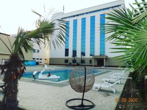 纳曼干OydinPlaza Hotel的一座带游泳池和棕榈树的大型建筑