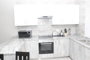 KitweRoyal Luxury Hotels and Apartments的白色的厨房设有水槽和炉灶。