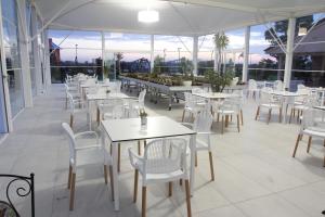 梅坦蓬托AGRITURISMO CASA RICOTTA的餐厅设有白色的桌椅和窗户。