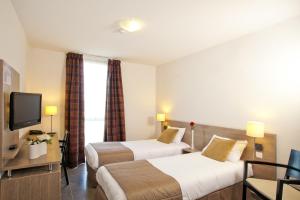 马诺斯克Apparthotel Séjours & Affaires Manosque的酒店客房设有两张床和电视。