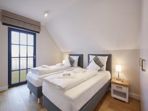 德兰斯克Reetland am Meer - Luxus Reetdachvilla mit 3 Schlafzimmern, Sauna und Kamin F08的带大窗户的客房内的两张床