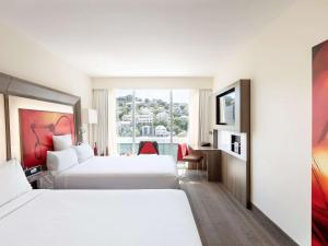 惠灵顿惠灵顿诺富特酒店的酒店客房设有两张床和窗户。
