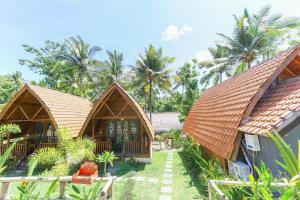 珀尼达岛Nyuh Gading Bungalow Nusa Penida的拥有2间小屋和棕榈树的度假村