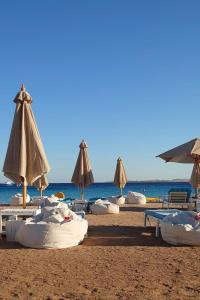 赫尔格达Tawaya Sahl Hasheesh的海滩上的一组沙滩椅和遮阳伞