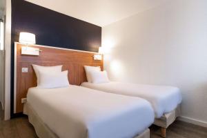 朗吉斯Comfort Hotel ORLY-RUNGIS的两张睡床彼此相邻,位于一个房间里