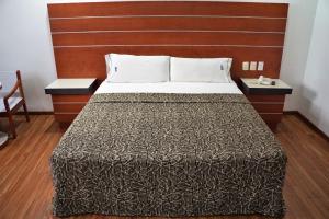 墨西哥城Hotel Duque的一间卧室配有一张大床和木制床头板