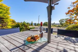 陶波Pokaka Lake House - Wharewaka Holiday Home的桌上的一盘食物和一瓶葡萄酒
