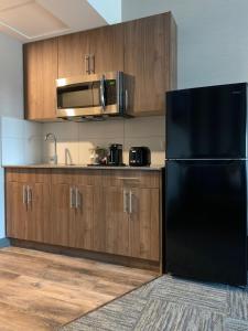 里贾纳Meridian Inn & Suites Regina Airport的厨房配有黑色冰箱和木制橱柜。