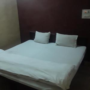 瓜廖尔shri bake bihari guest house的一张带两个枕头的大白色床