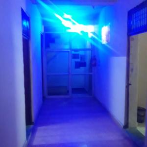 瓜廖尔shri bake bihari guest house的暗色走廊,有蓝色和绿色的灯光
