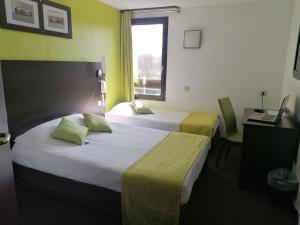 维耶尔宗Enzo Hotels Vierzon by Kyriad Direct的酒店客房设有两张床、一张书桌和一个窗户。