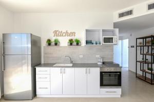提比里亚Europa Residence的厨房配有白色橱柜和不锈钢冰箱